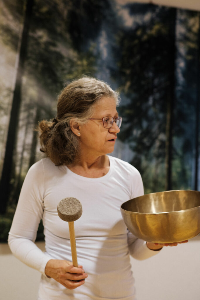 Yoga-Lehrerin Angela Kiesewetter-Lorenz in weißer Kleidung mit Klangschale