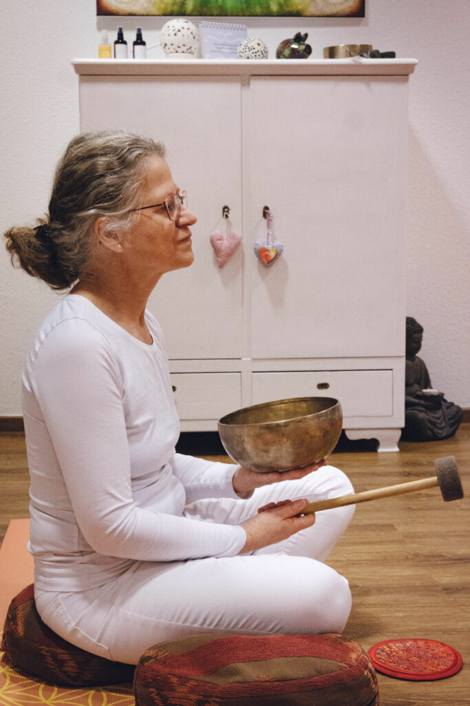 Yoga-Lehrerin Angela Kiesewetter-Lorenz in weißer Kleidung im Schneidersitz von der Seite fotografiert