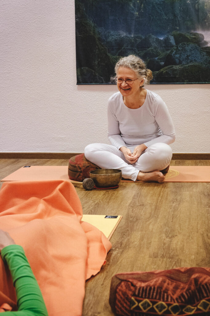 Yoga-Lehrerin Angela Kiesewetter-Lorenz, im Schneidersitz, lachend