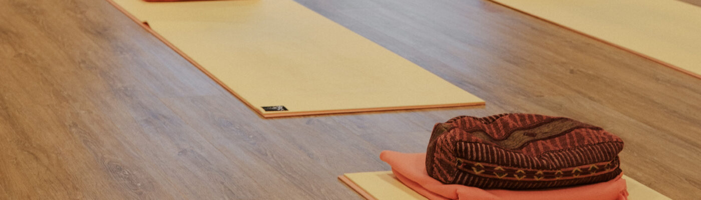 Yogamatten mit Decken und Kissen auf Parkettboden